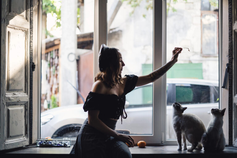 Pretty woman playing with siamese cats —