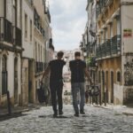 Two tourists walking down a cobblestone street in a historic district, representing how tourism can generate funds for big cat conservation through eco-tourism initiatives and wildlife preservation efforts.