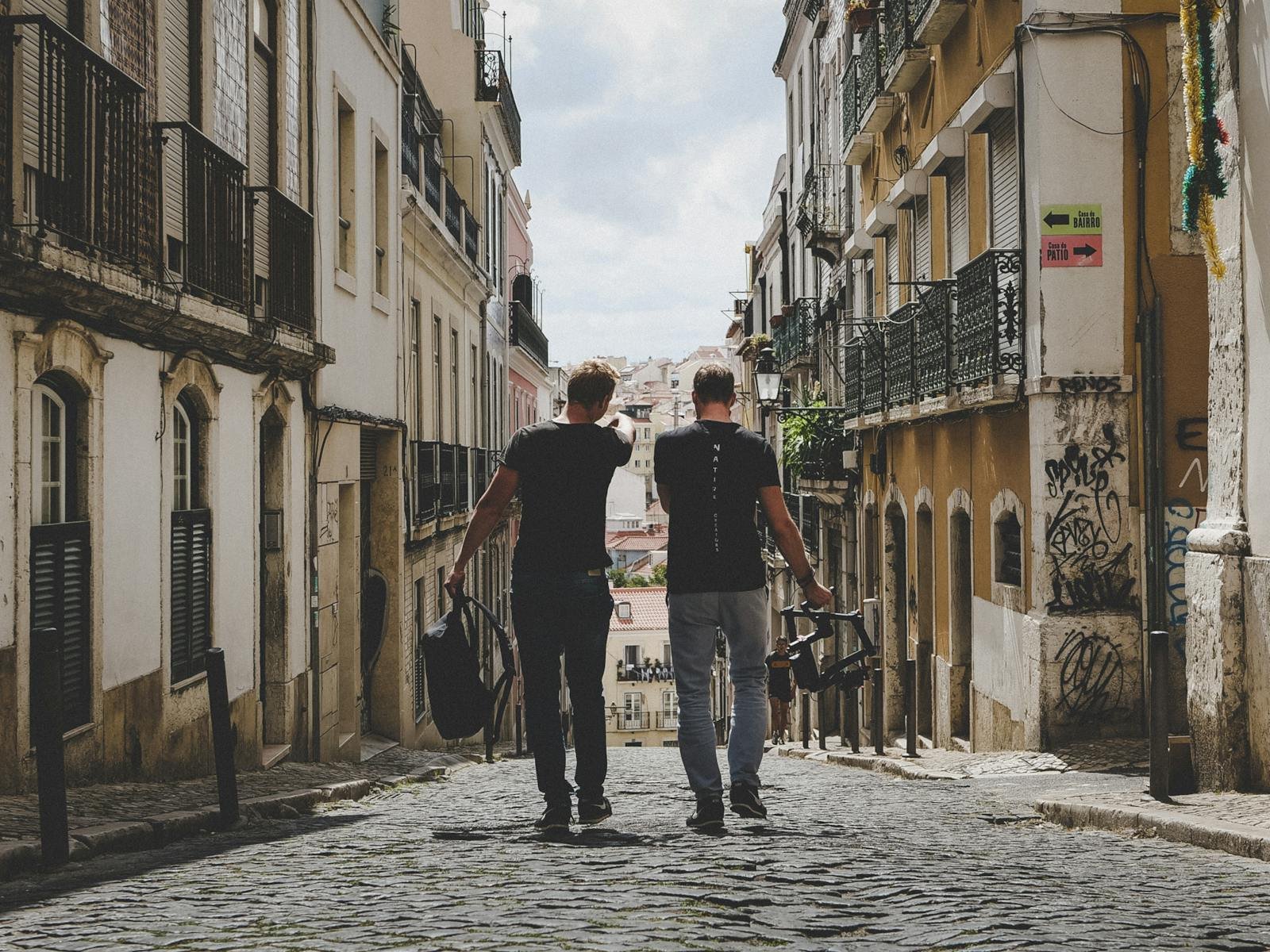 Two tourists walking down a cobblestone street in a historic district, representing how tourism can generate funds for big cat conservation through eco-tourism initiatives and wildlife preservation efforts.