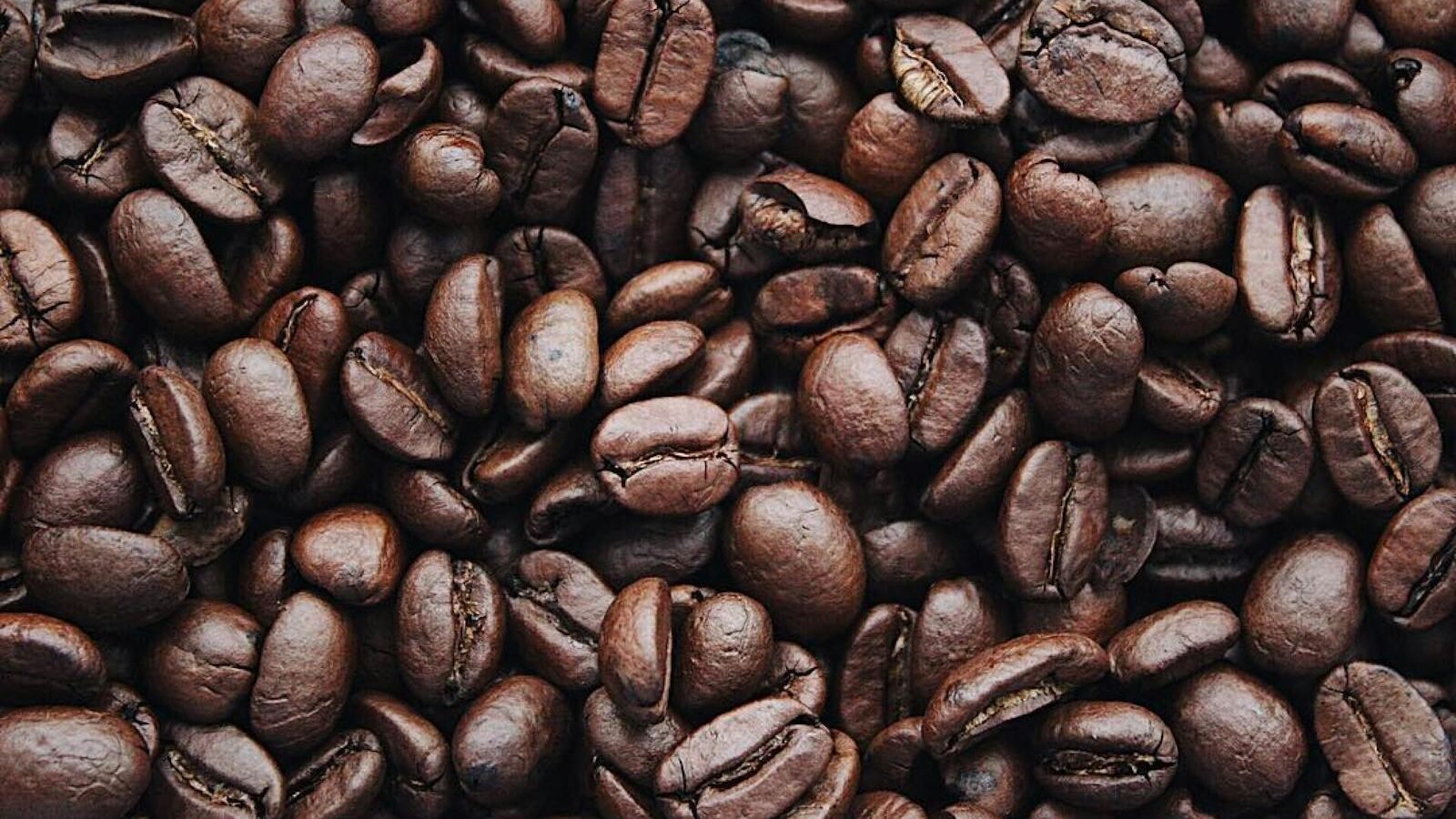 A close-up view of roasted coffee beans, showcasing their rich brown color and textured surface. The beans are tightly packed, symbolizing the essence of caffeine.