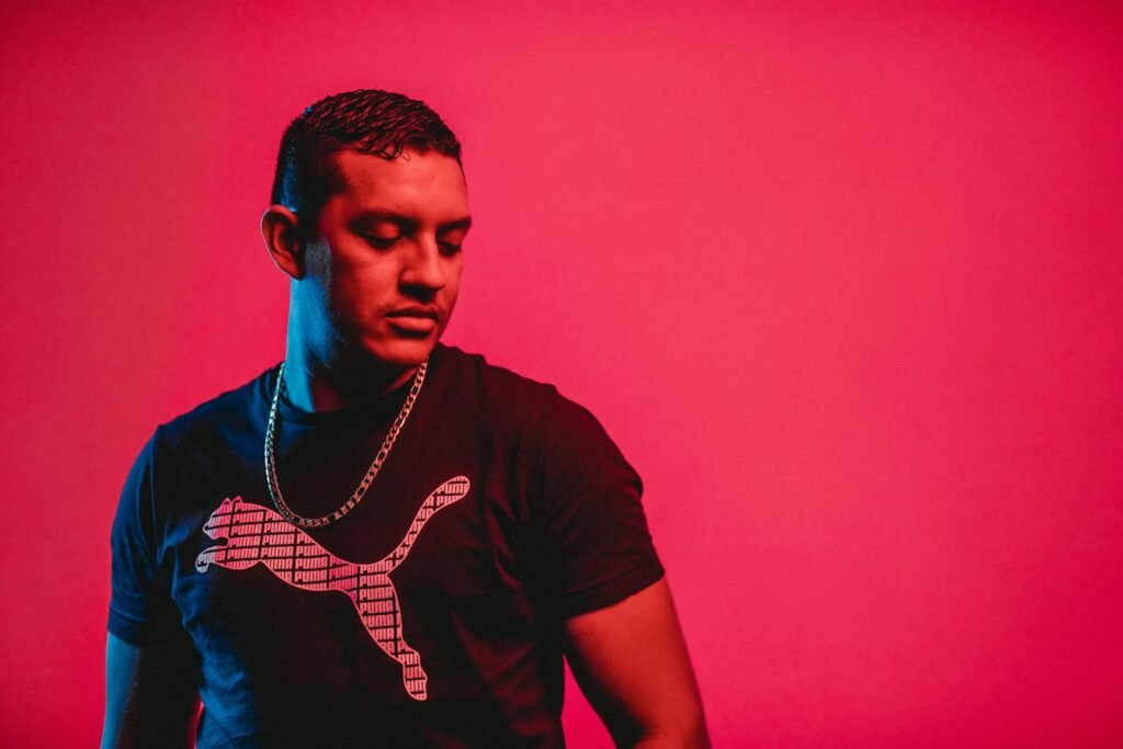 A portrait of a man against a vibrant red background, showcasing modern fashion and style.