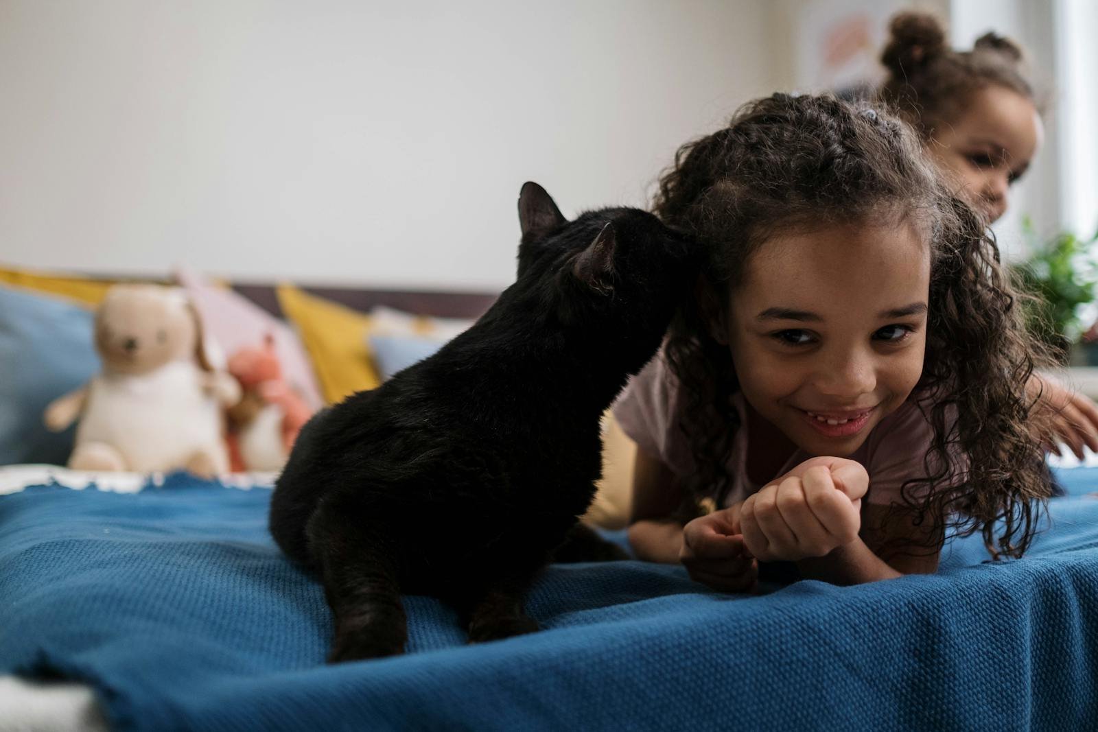 A delightful scene of a child sharing a loving moment with a black cat indoors.