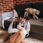 cats and humans: A serene scene of a woman with cats, enjoying a cozy indoor moment on a sofa.