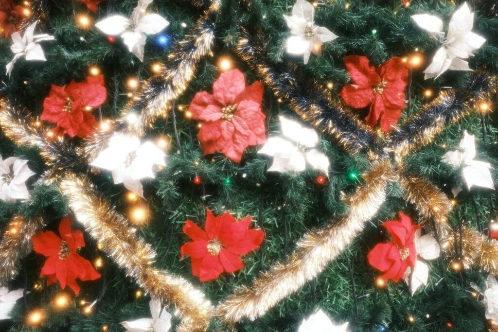 Colorful Christmas tree adorned with red poinsettias, tinsel, and lights for a festive holiday atmosphere.