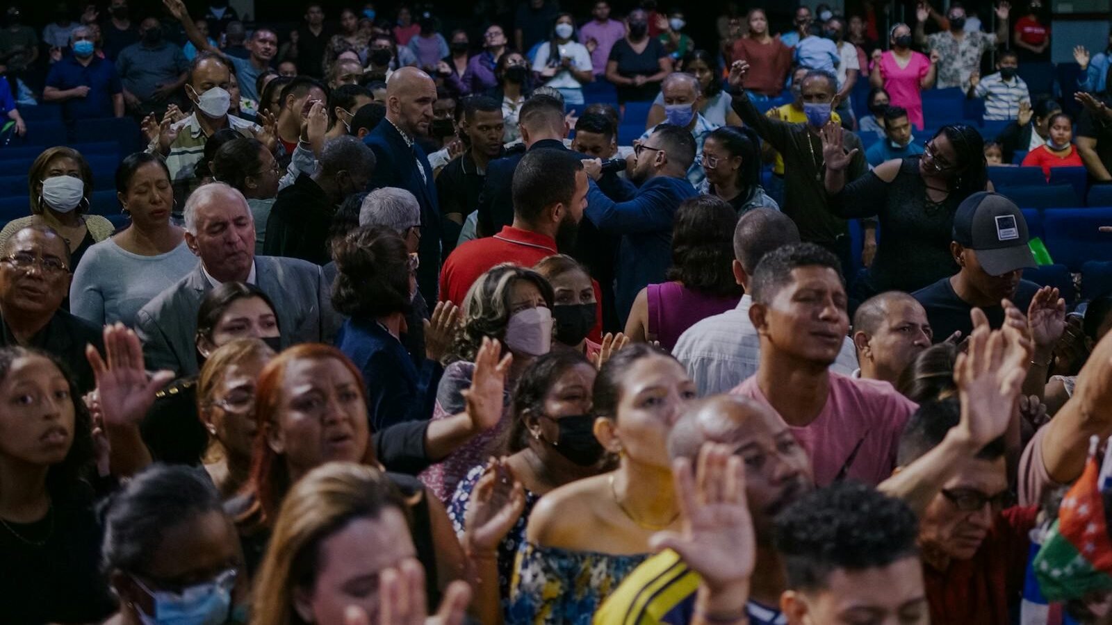 A diverse group of people gathered in a large auditorium, actively participating in an event focused on education and community awareness, reflecting engagement and shared learning