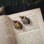 Vintage book pages adorned with gold and silver tiger-shaped brooches.