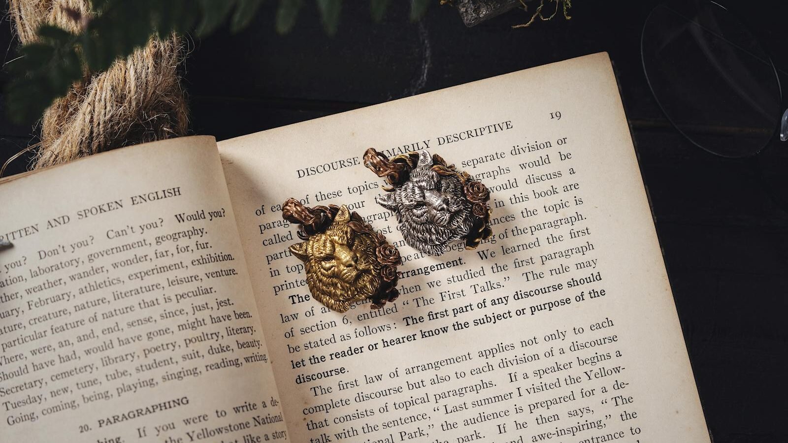 Vintage book pages adorned with gold and silver tiger-shaped brooches.