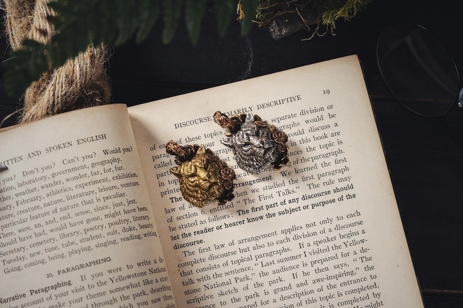 Vintage book pages adorned with gold and silver tiger-shaped brooches.