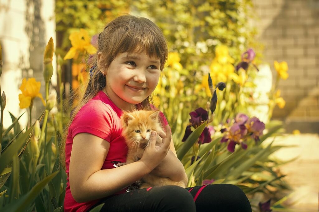 A happy girl holding a kitten surrounded by colorful irises in a garden.