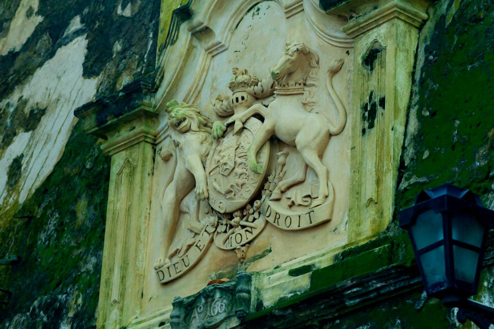 Intricate stone sculpture of a royal emblem on a historic building in Galle Fort, Sri Lanka.