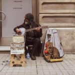 Elderly musician playing cumbus on Istanbul street with a cat beside him.