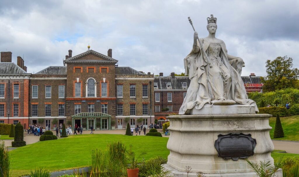 Kensington Palace with Queen Victoria statue, showcasing British heritage and architecture.