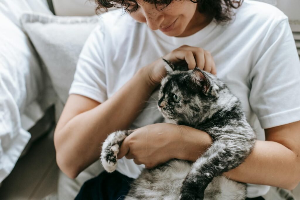 A woman lovingly cuddling her pet cat on a cozy day indoors.
