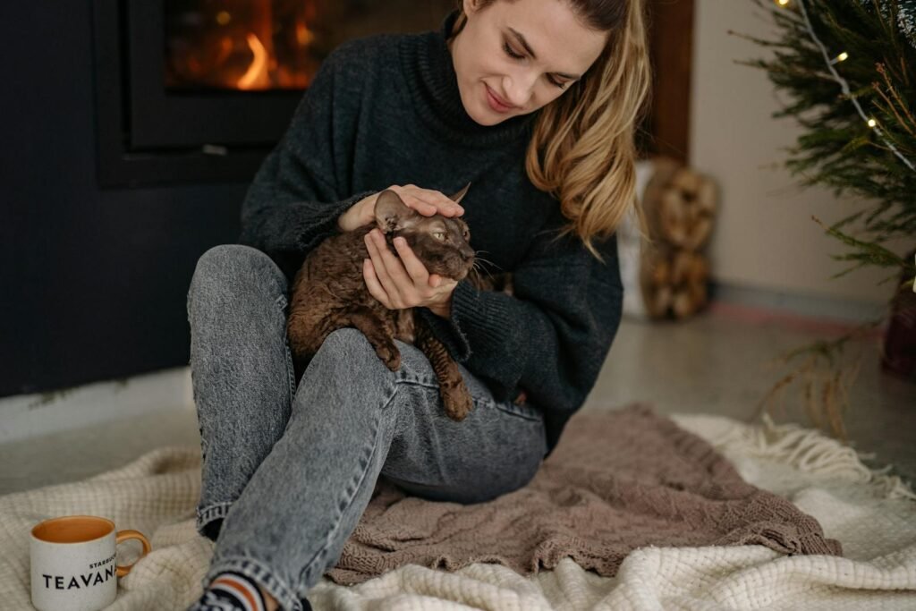 A woman lovingly caressing her cat by the warm fireplace indoors.