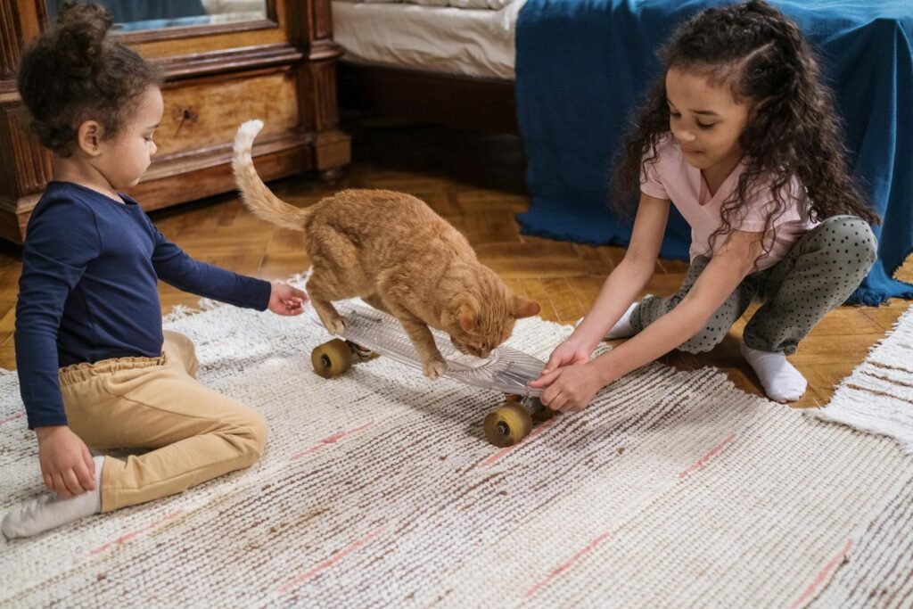 Two children and a ginger cat having fun with a skateboard in a cozy indoor setting.