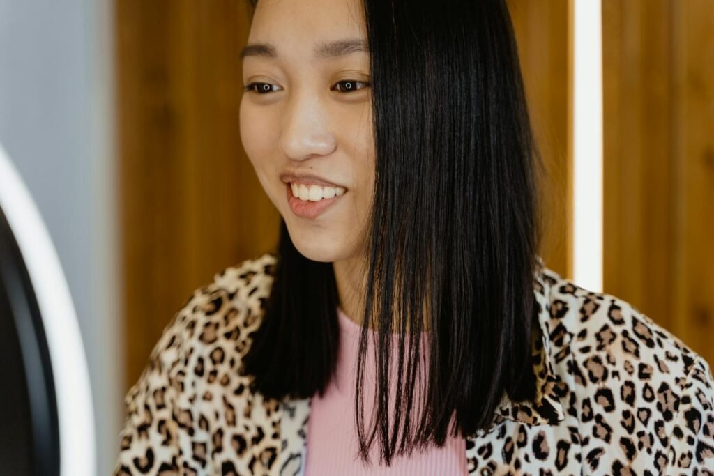Close-up of a smiling young woman with black hair in a cheetah print shirt.
