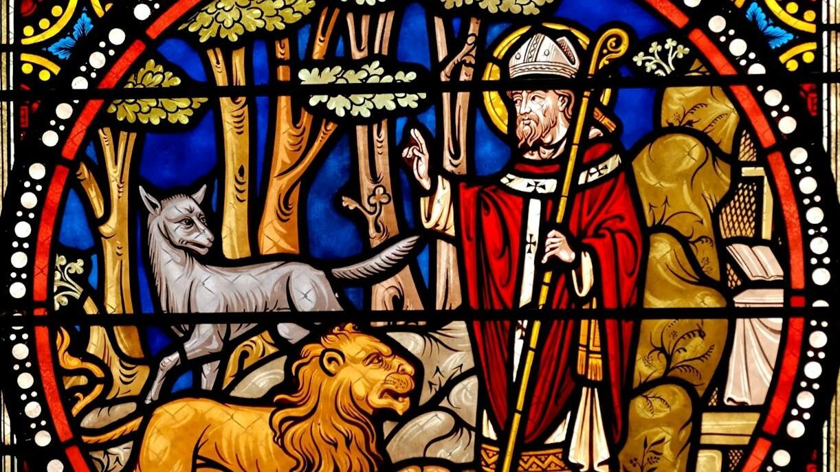 Vibrant stained glass window showcasing a saint with animals in a church setting.
