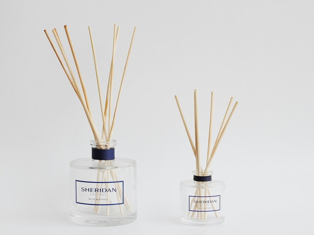 two bottles with reeds in them on a white surface
