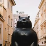 A statue of a cat sitting in the middle of a street