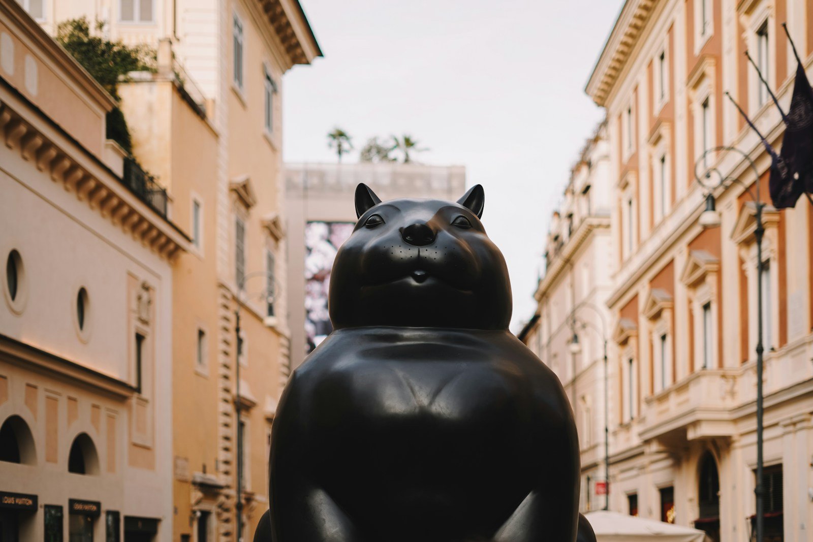A statue of a cat sitting in the middle of a street