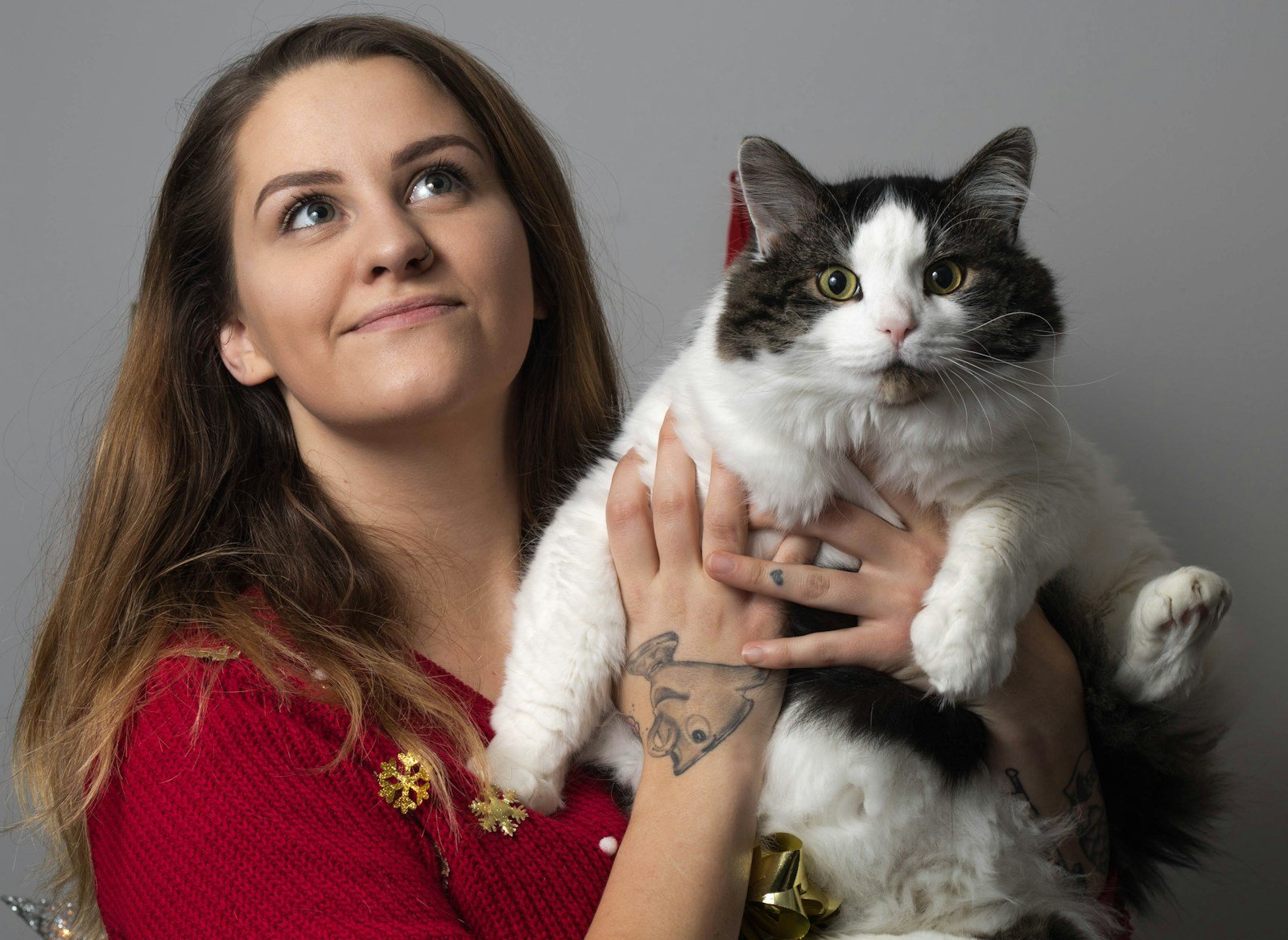 Photo by Jonathan Cooper woman in red knit sweater holding white and black cat
