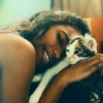 woman lying beside cat while smiling