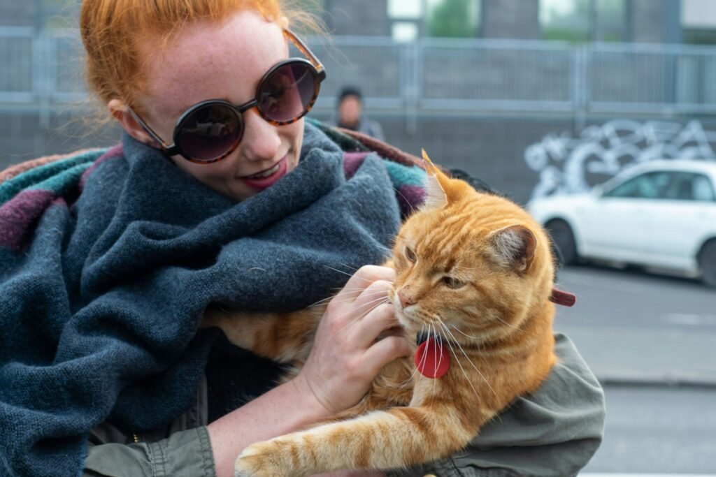 a woman with red hair is holding a cat