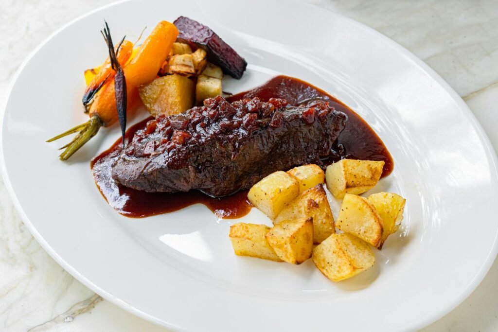 Gourmet beef in rich sauce with roasted vegetables and potatoes.