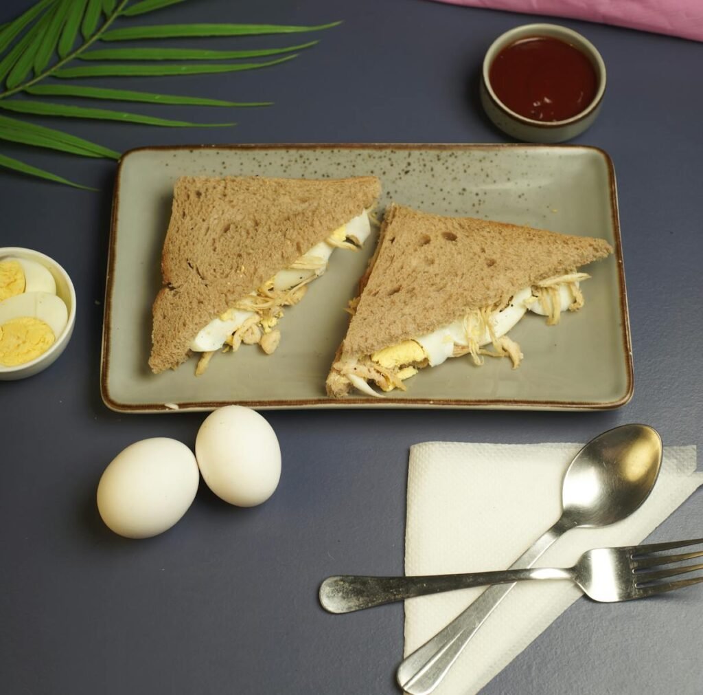 Tasty egg sandwich with sliced boiled eggs served on a ceramic plate.