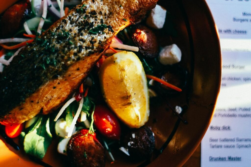 Close-up of a grilled salmon salad garnished with fresh vegetables and lemon.