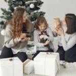 A family with children and cats celebrating Christmas by the tree with gifts.