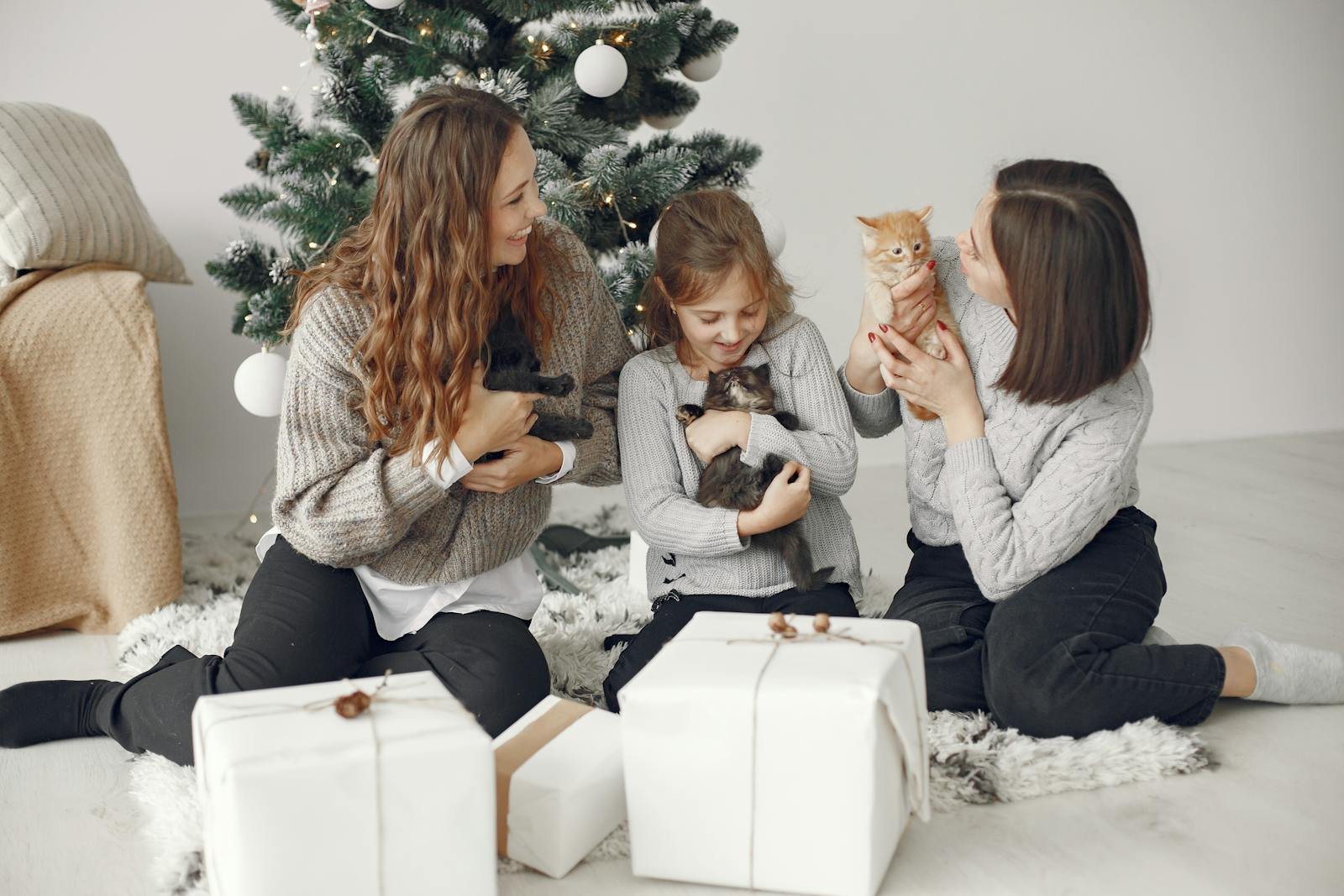 A family with children and cats celebrating Christmas by the tree with gifts.