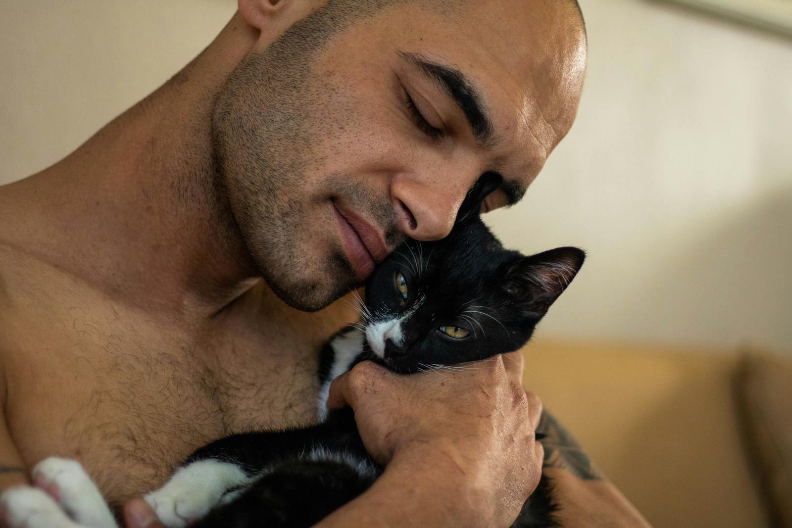A man gently holds a black and white cat in an intimate moment of affection.