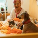 Senior woman enjoying the company of a dog and cat in a cozy bedroom setting, showcasing warmth and companionship.