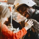 Smiling firefighter and child petting a cat indoors, creating a warm and joyful scene.