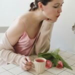 a person sitting on a chair with a cat and a cup of tea